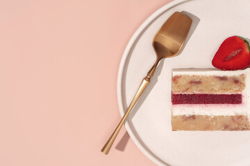 Bento cake slice on a minimalist plate with a golden serving utensil and fresh strawberry, showcasing vibrant layers and textures in a visually appealing dessert presentation concept