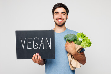 Young happy man wears blue t-shirt casual clothes hold bunch of lettuce salad show card with vegan...
