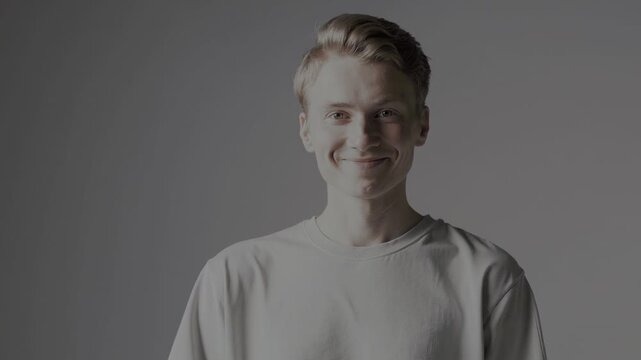 Clean-cut man in a white tee, looking directly at the camera against a gray background