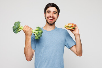 Young man wear blue t-shirt casual clothes hold broccoli pov dumbbell choose between vegetables and...
