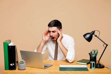 Young shocked sad mad employee IT business man he wear white shirt tie sit work at office desk use...