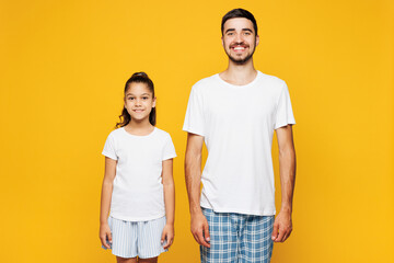 Young smiling happy parent man have fun with child girl in casual blue pyjamas clothes. Daddy little kid daughter looking camera isolated on plain yellow background. Father's Day Love family concept.
