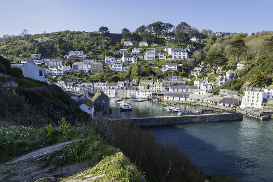 Looe, United Kingdom - 04 October 2025: View of the harbor's tranquil waters, where fishing boats rest against the backdrop of the town's quaint buildings nestled on the hillside..