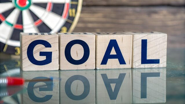 Achieving goals conceptual image depicting the word goal with dartboard in the background representing business success and target achievement