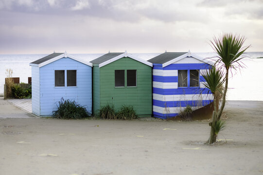 View of vibrant beach huts stand cheerfully on golden sands under a soft sky, a tranquil coastal scene, Looe, Cornwall, United Kingdom.