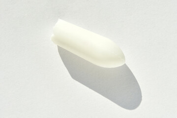White suppository with shadow on light background highlighting its shape and texture.