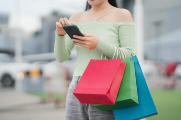 Shopping spree: A stylish individual, clutching vibrant shopping bags, engrossed in a handheld...