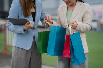 Shopping Day Delight: Two stylish women, one holding a tablet, the other excitedly admiring a...