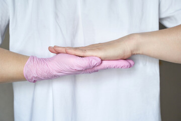 Female caucasian adult hands pressing together with protective pink glove against white background.