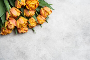 Vibrant bouquet of orange tulips arranged elegantly on a textured gray surface, showcasing the...