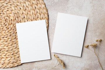 Two blank white invitation or greeting cards mockup with copy for design purposes on a round woven...