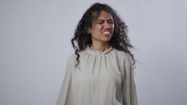 South Asian woman with curly hair, nods her head to signify "no", with a disapproving face