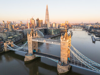 Aerial view of the majestic Tower Bridge over the shimmering Thames River, with the Shard piercing the skyline in the distance, London, United Kingdom.