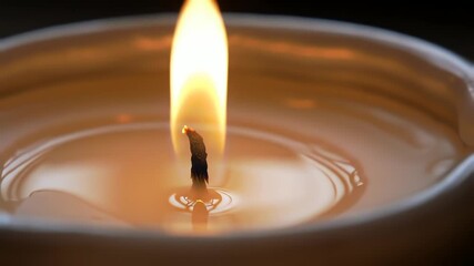 Lit candle's wick with a bright, warm flame burning steadily in melted wax - Powered by Adobe