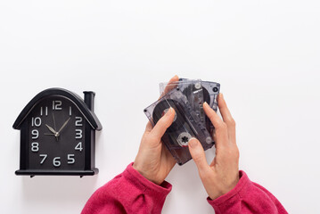 Closeup of hands with old watch and audio cassette saving musical memories of past. Hands holding...