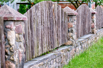 Wooden fence designed with stone base showcases craftsmanship in a peaceful garden setting during...
