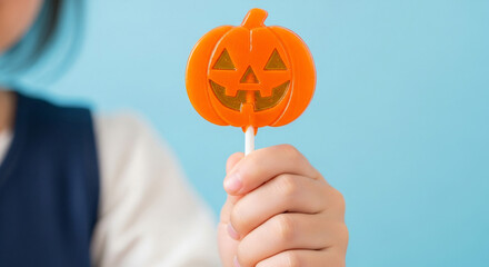 Cute Child Holding Orange Halloween Pumpkin Lollipop with Blue Backdrop