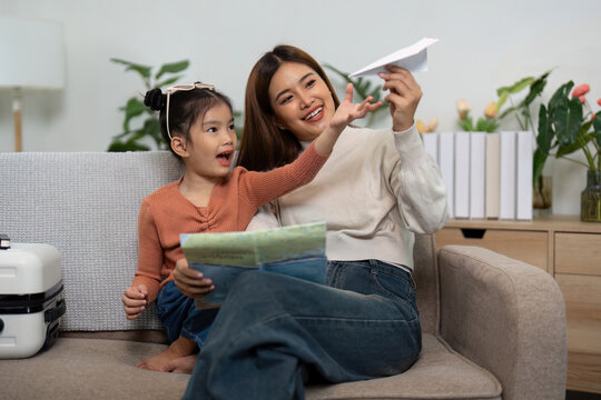 Travel Creativity. Mother and daughter making paper airplanes while preparing for their trip.