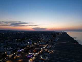 Coastal City Dusk: An aerial perspective captures a coastal city at dusk, where the city's glowing lights meet the serene, pastel hues of the sunset sky, creating a harmonious contrast.