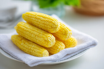Freshly cooked sweet corn on the cob stacked on a white plate