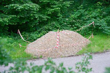 Gravel Pile with Caution Tape in Forested Area