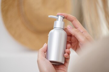 Woman applying luxurious lotion to her hands in a modern bathroom for skincare wellness
