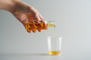 Golden liquid elegantly pouring into glass for culinary uses or healthy lifestyle concepts