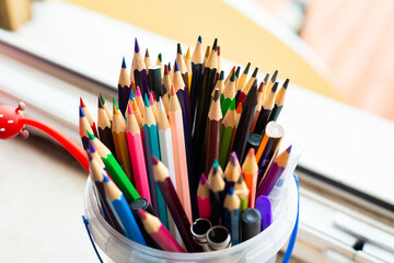 A bucket filled with assorted colored pencils and scissors