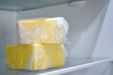 Cheese with plastic wrap in the fridge. The concept of how to store cheese properly.