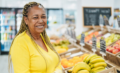 African female customer buying organic food fruits inside eco fresh local market - Healthy lifestyle and small business concept - Focus on face