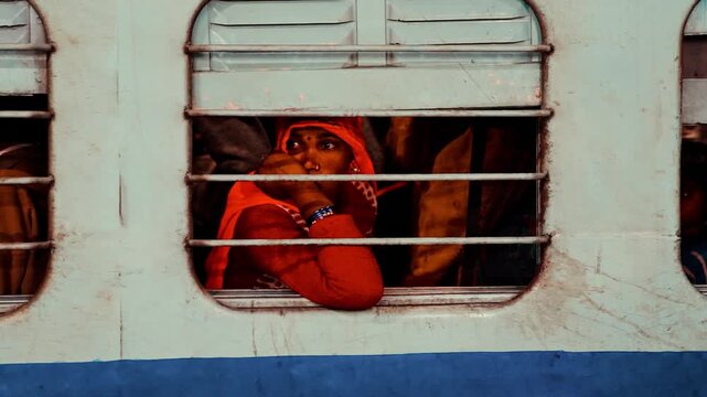 Woman looking out from an old Indian train. A nostalgic travel moment capturing everyday life and rail journey in India. 27 January 2020, Varanasi, India.