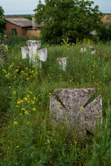 Ancient stone Christian crosses in an old cemetery among the grass. Nameless tombstone
