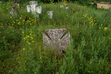 Ancient stone Christian crosses in an old cemetery among the grass. Nameless tombstone