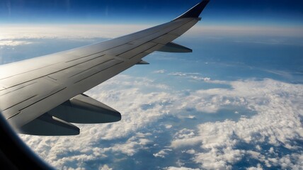 Fototapeta premium View from airplane window showing clouds below and wing