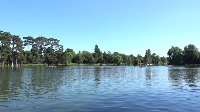 Vue sur un &eacute;tang &agrave; barques du bois de Boulogne en &eacute;t&eacute; par temps bleu ensoleill&eacute;