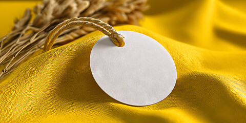 White tag with string on yellow fabric and dried flowers