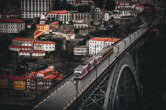 Porto, Portugal - 17 June 2022: View of a modern train gracefully traversing the Dom Lu&Atilde;&shy;s I Bridge against a backdrop of historical buildings.