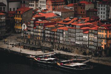 Porto, Portugal - 17 June 2022: View of the Ribeira district's colorful buildings cascade down to the Douro River, where traditional boats rest, their dark hulls contrasting with the vivid facades.