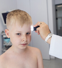 A pediatric dermatologist examining a young boys skin with a dermatoscope in a medical clinic. Skin...