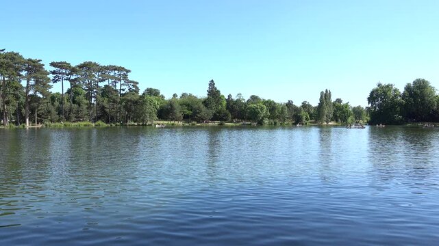 Vue sur un &eacute;tang &agrave; barques du bois de Boulogne en &eacute;t&eacute; par temps bleu ensoleill&eacute;