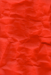 Fototapeta premium Crumpled red paper featuring a vivid hue with visible folds and wrinkles. The texture is irregular, providing a realistic, tactile appearance. Suitable for use in design templates, such as flyers.