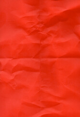 Crumpled red paper with a textured surface, displaying numerous organic creases and folds. The...