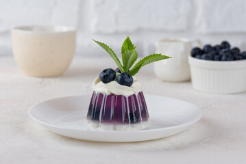 Jelly dessert with anchan tea, blueberries, mint and cream on light table. Vegan, sugar and lactose free.