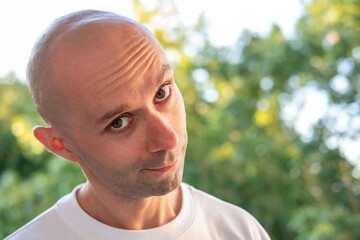 Thoughtful young Bald man looking up contemplating in soft natural light, Portrait adult male,...