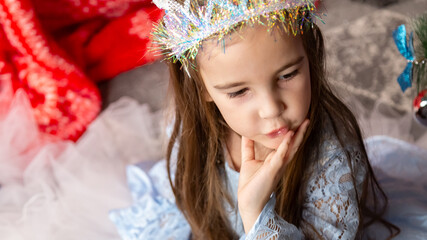 Christmas time, cute children play cuddling and having fun sitting on the floor near the festive...