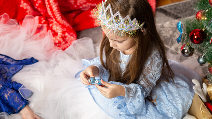Christmas time, cute children play cuddling and having fun sitting on the floor near the festive Christmas tree