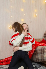 Christmas at home and daughter with mother hugs in the living room.