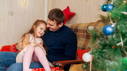 Father and daughter playing together in front of the Christmas tree