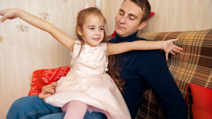 Father and daughter playing together in front of the Christmas tree