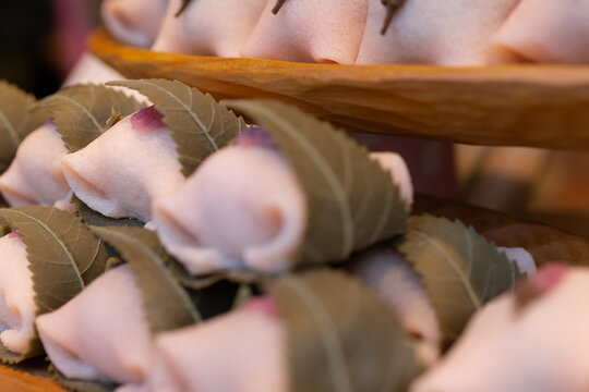 Aerial view of delicate pink sakura mochi, each wrapped in a vibrant green leaf, showcasing the artistry of Japanese confectionery, Tokyo, Tokyo, Japan.